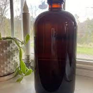 May include: A large amber glass bottle with a black lid. The bottle is filled with a clear liquid.