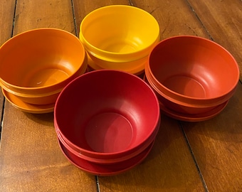 May include: Set of four nesting bowls in shades of orange, red, and yellow. The bowls are made of plastic and are stackable for easy storage.