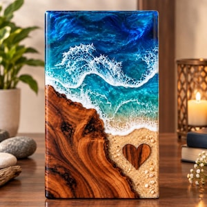 May include: A rectangular resin art piece featuring a realistic ocean scene with deep blue and turquoise waves crashing onto a sandy shore. The composition includes a natural wood grain section on the left and a small wooden heart embedded in the sand.