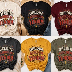 Può includere: Una collezione di sei magliette a maniche corte in crema, nero, bordeaux, grigio scuro, giallo e verde oliva. Ogni maglietta presenta una stampa grafica con il testo GELDIM, GORDUM ve YENDIM, circondato da stelle, fulmini e foglie decorative.