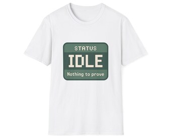 May include: A white short-sleeve t-shirt featuring a dark green rectangular graphic on the chest. The graphic displays the pixelated text "STATUS" at the top, the word "IDLE" in large white letters in the centre, and "Nothing to prove" below.