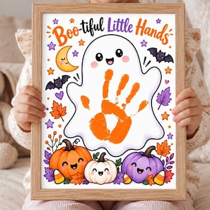 May include: A framed print featuring the text Boo-tiful Little Hands at the top, a central white ghost illustration with an orange handprint in the middle, and colourful cartoon pumpkins, bats, stars, and autumn leaves surrounding the ghost.