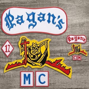 May include: A collection of embroidered patches including a large white rocker with blue text reading Pagan's, a yellow and red graphic patch, a diamond-shaped 1% patch, two square patches with blue letters M and C, and smaller matching logo patches.