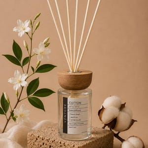 May include: A clear glass reed diffuser bottle with a wooden cap and six reeds. The label reads VENTORE, COTTON, 100 ml/3.4 fl oz, Reed diffuser, fresh linen, jasmine, white musk, Handcrafted in Oxford, Batch 001. Accompanied by white flowers and cotton.