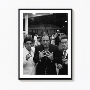 Può includere: Una stampa fotografica in bianco e nero incorniciata che ritrae tre uomini in abito, due dei quali tengono dei sigari. La figura centrale fa un gesto con la mano mentre gli altri sono accanto a lui. Sullo sfondo una stazione di servizio.