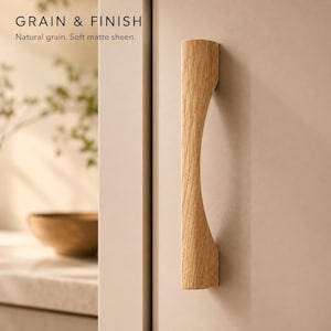 May include: A light-coloured wooden cabinet handle with a curved, concave profile and visible wood grain. The text GRAIN & FINISH and Natural grain. Soft matte sheen. is printed in the upper left corner of the image.