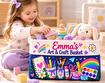 May include: A rectangular fabric storage basket with a dark blue base and white top section. The text Emma's Art & Craft Basket is printed on the front, surrounded by colorful illustrations of art supplies, rainbows, and hearts.