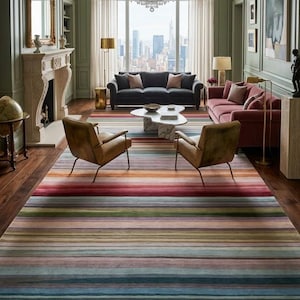 May include: A large rectangular area rug featuring a horizontal striped pattern in a palette of muted red, blue, green, pink, and tan tones. The rug has a low-pile texture and covers the floor of a living room, extending from the foreground.