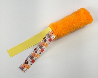 Può includere: Giocattolo di peluche arancione con un nastro giallo e un nastro con un motivo di gatti colorati.