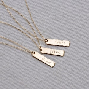 Puede incluir: Tres collares de oro con un colgante de barra martillada. Cada colgante está grabado con el número "90266".