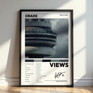 May include: A framed poster featuring the Drake album Views, dated April 29, 2016. The design includes a photograph of the CN Tower, a tracklist of twenty songs, the title VIEWS, and a signature. The color palette is black, white, and gray.