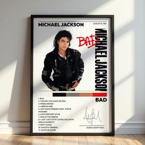 Puede incluir: Un póster enmarcado con Michael Jackson en una chaqueta negra con hebillas. El texto dice Michael Jackson, Bad, 31 de agosto de 1987, y enumera once canciones incluyendo Bad y Man in the Mirror. Se incluyen una firma y una paleta de colores.