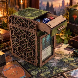 Könnte beinhalten: Eine hölzerne Deck-Box mit lasergeschnittenem Blattmuster an den Seiten und einem Baummotiv auf dem Deckel. Die Box verfügt über eine ausziehbare Schublade mit Würfeln und einen vorderen Sichtschlitz, in dem eine Sammelkarte steckt.