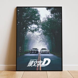 Könnte beinhalten: Ein gerahmtes vertikales Poster mit zwei weißen Sportwagen, die auf einer asphaltierten Straße durch einen dichten, nebligen Wald fahren. Der große weiße japanische Schriftzug Initial D steht unten, mit zusätzlichem vertikalem japanischem Text links.