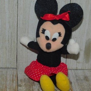 May include: A black and red plush toy of Minnie Mouse with a red bow, white eyes, and a red and white polka dot skirt.