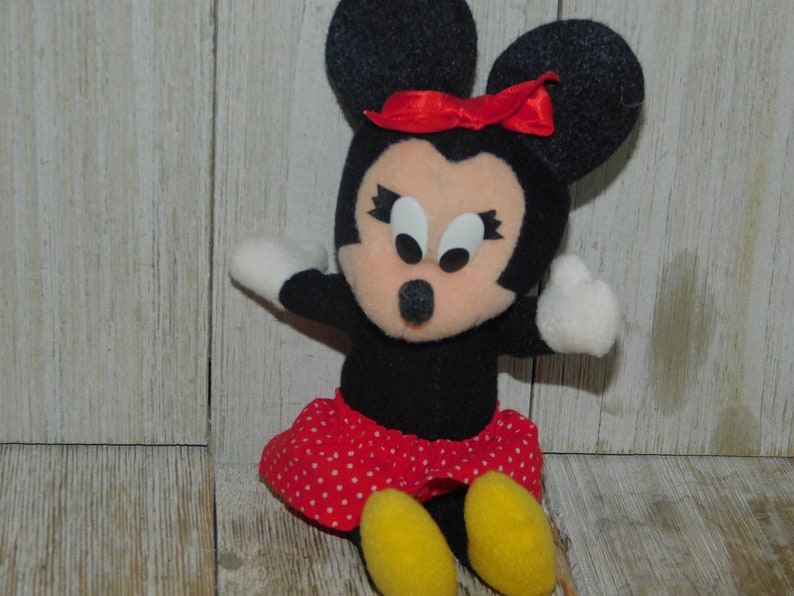 May include: A black and red plush toy of Minnie Mouse with a red bow, white eyes, and a red and white polka dot skirt.