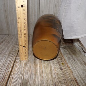 May include: A brown ceramic vase with a textured surface and a gold-colored base. The vase is approximately 6 inches tall.