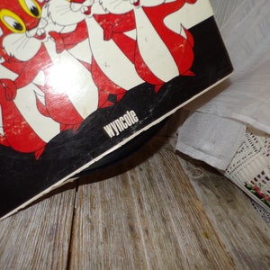 Puede incluir: Una portada de disco de vinilo en blanco y negro con una imagen de dibujos animados de cinco ardillas rojas. La portada del disco tiene el texto "Wyncote" impreso en la esquina inferior derecha.