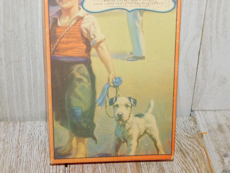 May include: A vintage illustration of a young boy in a red and white striped vest and blue pants walking a small white dog with a blue ribbon around its neck. The boy is holding the ribbon in his hand and the dog is looking up at him. The background is a light yellow color.