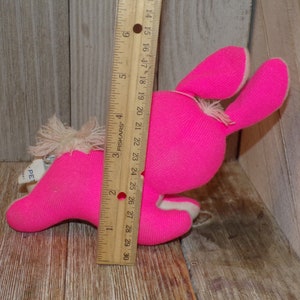 May include: A pink plush bunny toy with white fur accents. The bunny is lying on its side with its head turned to the right. The toy is approximately 7 inches long.
