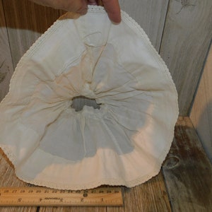 May include: A white cotton petticoat with a lace trim. The petticoat is gathered at the waist and has a ruffled hem.
