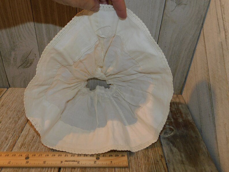 May include: A white cotton petticoat with a lace trim. The petticoat is gathered at the waist and has a ruffled hem.