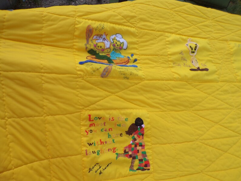 May include: Yellow quilted blanket with embroidered cartoon figures and text. Features a couple in a boat, a cartoon bird, and a couple embracing. The text reads "Love is the most fun you can have without laughing."