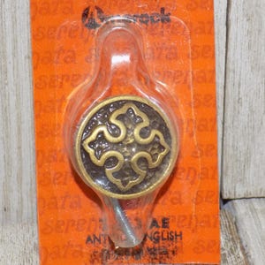 May include: A gold-toned metal hook with a decorative design featuring four stylized leaves. The hook is packaged on a bright orange card with the text "Antique English" printed on it.