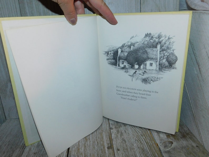 May include: A black and white illustration of a cottage with a thatched roof, surrounded by trees and a stone wall. The text "PETER AND ANDREW were playing in the thone yond when they heard thes Candmother calling to them. Prel Andew" is printed below the illustration.