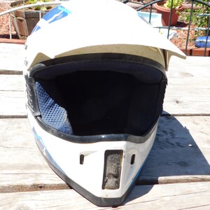 May include: White motorcycle helmet with blue and black accents. The helmet has a visor and a black interior lining.