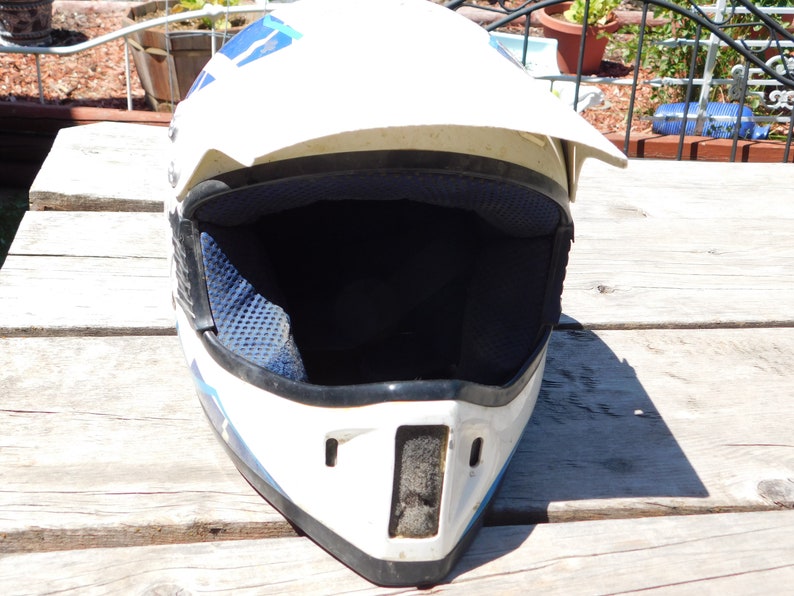 May include: White motorcycle helmet with blue and black accents. The helmet has a visor and a black interior lining.