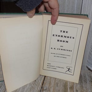 May include: A green hardcover book titled "The Enormous Room" by E.E. Cummings. The book is part of the Modern Library series and includes an introduction by the author.