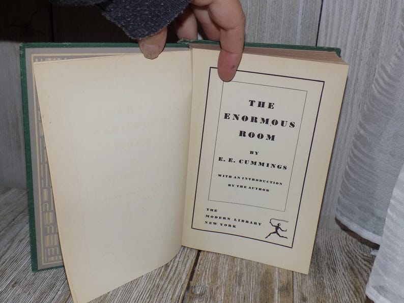 May include: A green hardcover book titled "The Enormous Room" by E.E. Cummings. The book is part of the Modern Library series and includes an introduction by the author.
