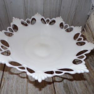 May include: White milk glass pedestal cake plate with a delicate lace design around the edge.