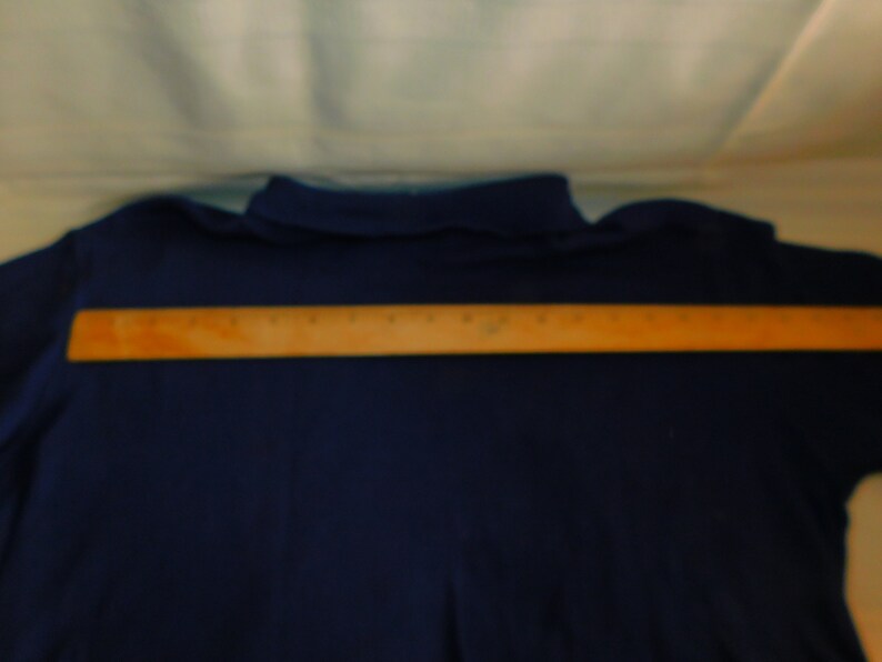 May include: A navy blue long-sleeved shirt with a wooden ruler placed across the back.