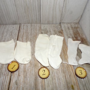 May include: Three pairs of white socks, two pairs are ankle socks and one pair is knee-high socks.