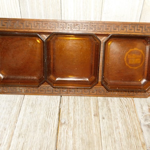 May include: A wooden serving tray with three amber glass dishes. The tray has a decorative Greek key border. The center dish has a "Wilton" logo.
