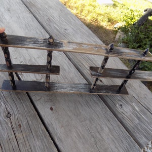 May include: A three-tiered wooden shelf with black and white paint. The shelf is made of wood and has a distressed look. The shelf is perfect for displaying small items.