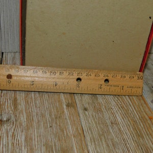 May include: A close-up of a wooden ruler measuring 30 inches. The ruler is made of wood and has black markings. The ruler is on a wooden surface.