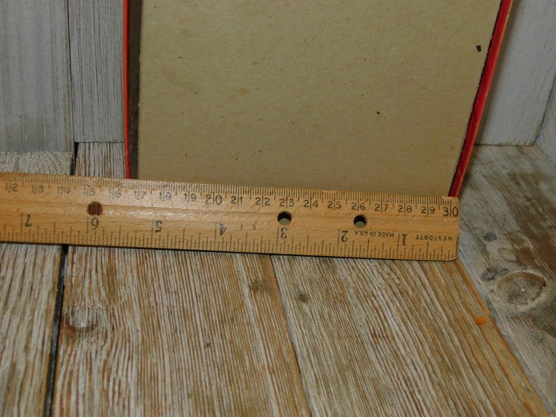 May include: A close-up of a wooden ruler measuring 30 inches. The ruler is made of wood and has black markings. The ruler is on a wooden surface.
