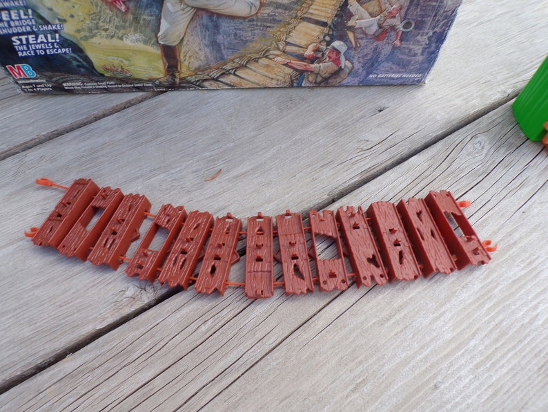 May include: A brown plastic bridge made of multiple pieces, each with a textured surface. The bridge is designed to be used with a board game.