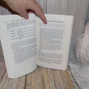May include: A close-up of a book open to a page with the title "Games for Two Players". The text describes the history of card games and how they are played.