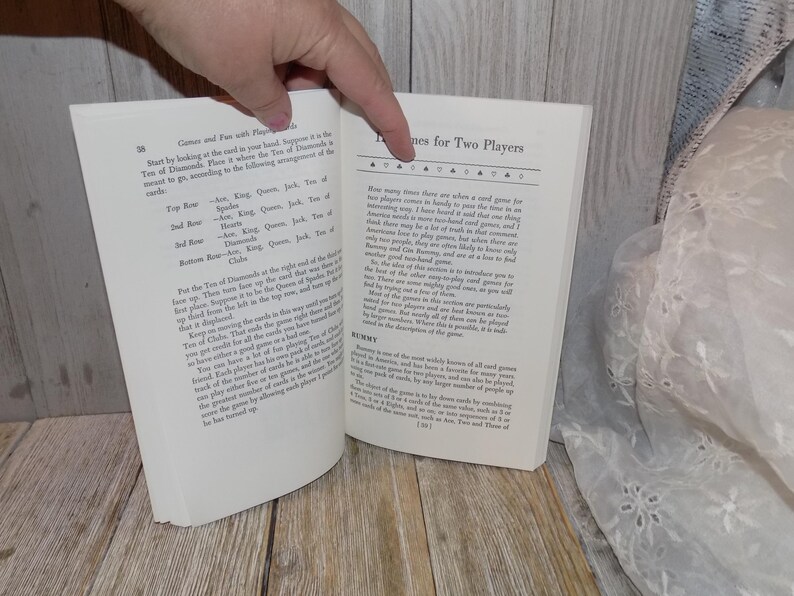 May include: A close-up of a book open to a page with the title "Games for Two Players". The text describes the history of card games and how they are played.