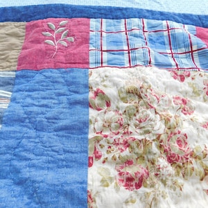 May include: A patchwork quilt with a blue, red, white, and brown color scheme. The quilt is made of different fabrics, including plaid, floral, and striped patterns.