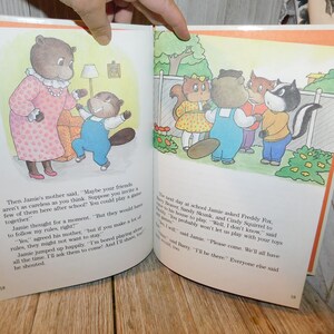 May include: A children's book illustration featuring a group of animal characters, including a beaver, a fox, a skunk, and a squirrel. The animals are standing in a backyard setting with a fence and flowers. The text on the page reads, "The next day at school Jamie asked Freddy Fox, Sandy Skunk, and Cindy Squirrel to come to his house to play. "Well, I don't know," said Cindy. "Teddy probably won't let us play with your toys anymore."  "But I will," said Jamie. "Please come. We'll all have fun."  "I'll be there." Everyone else said.