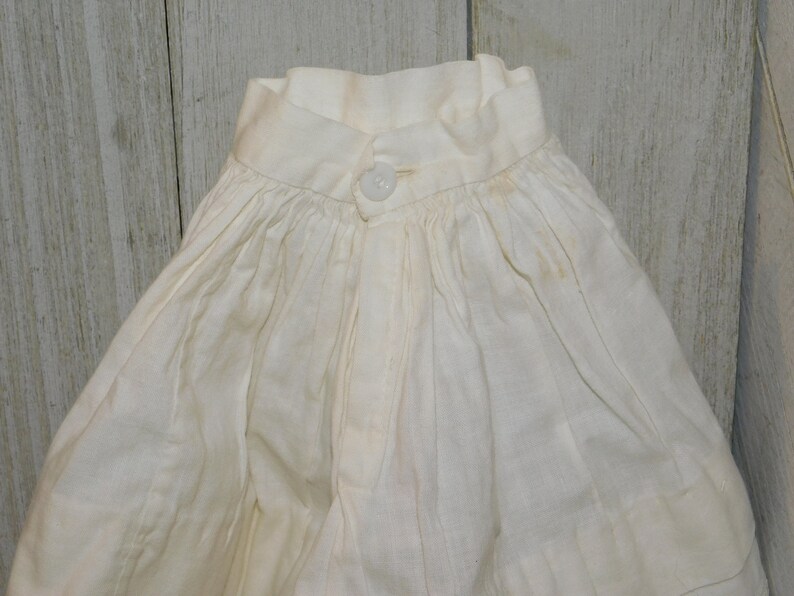 May include: A white cotton garment with a gathered skirt and a button fastening at the neck.
