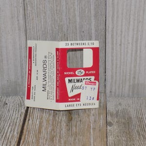 Pode incluir: Uma embalagem de cart&atilde;o branco com texto vermelho e preto para agulhas de olho grande Milwards Need 97. A embalagem diz "N&iacute;quel 15c  Prata" e "25 Betweens 5/10".