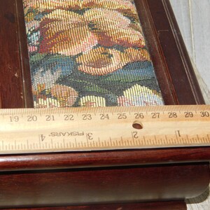 May include: A wooden box with a floral tapestry top. The box is 27 inches long and has a dark brown finish.