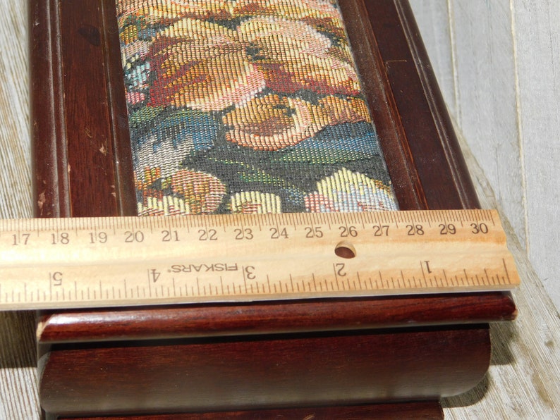 May include: A wooden box with a floral tapestry top. The box is 27 inches long and has a dark brown finish.