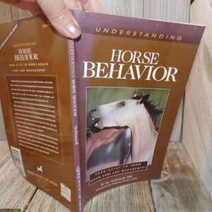 May include: A brown book titled "Understanding Horse Behavior" with a picture of two horses on the cover. The book is part of the "Horse Health Care Library" series and is by Sue McDonnell, PhD. The book's subtitle is "Your Guide to Horse Health Care and Management."
